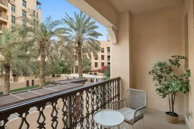 a balcony with a table and chairs and palm trees at FIRST CLASS 2BR Old Town Burj View Retreat in Dubai