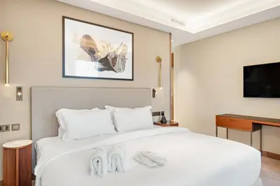 a bedroom with a white bed and a flat screen tv at FIRST CLASS 2BR Burj Khalifa & Fountain View in Dubai