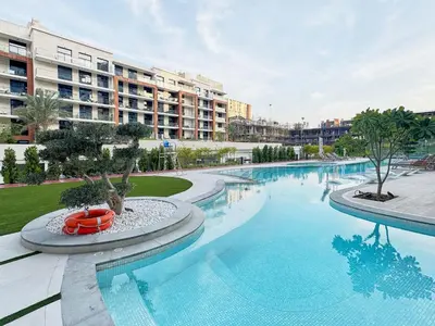 a large swimming pool in front of a large building at Modern Studio at Oxford Gardens Arjan - Near Miracle Garden in Dubai