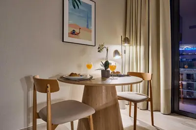a dining room table with chairs and wine glasses on it at Modern Studio at Oxford Gardens Arjan - Near Miracle Garden in Dubai