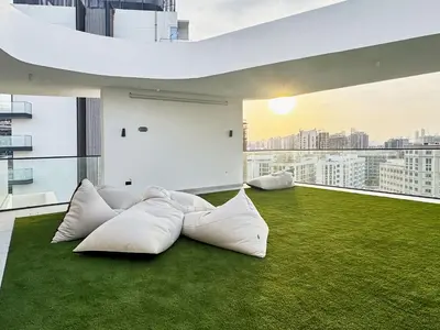 a living room with white pillows on the grass at Modern Studio at Oxford Gardens Arjan - Near Miracle Garden in Dubai