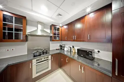 a large kitchen with wooden cabinets and a microwave at FIRST CLASS 1BR Sophisticated Downtown Escape in Dubai