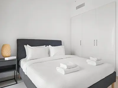 a white bedroom with a bed with towels on it at Elegant 2BDR Full BurjKhalifa View In Downtown-06 in Dubai