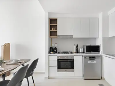 a kitchen with white cabinets and a table with chairs at Elegant 2BDR Full BurjKhalifa View In Downtown-06 in Dubai