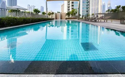 a swimming pool with blue tiles in a city at Elegant 2BDR Full BurjKhalifa View In Downtown-06 in Dubai