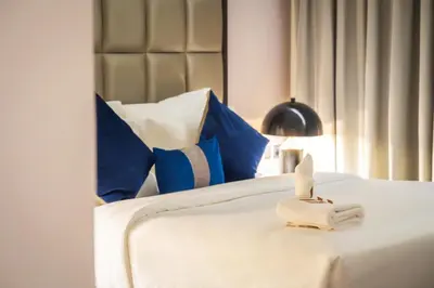 a white bed with blue pillows and a towel on it at Downtown Dubai Mall Walkable 8 min in Dubai