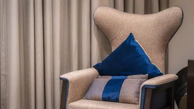 a blue pillow sitting on a chair with curtains at Downtown Dubai Mall Walkable 8 min in Dubai