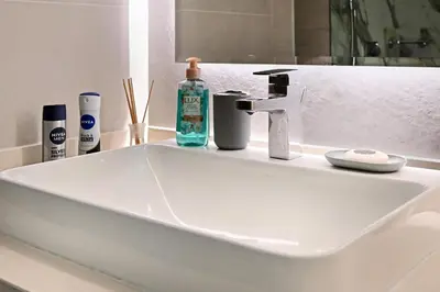 a white sink with a bottle of soap and toothpaste at Peaceful, Unique 1BR Experience ,Dubai Marina in Dubai