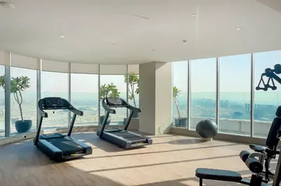 a gym with cardio equipment in a building with windows at Peaceful, Unique 1BR Experience ,Dubai Marina in Dubai