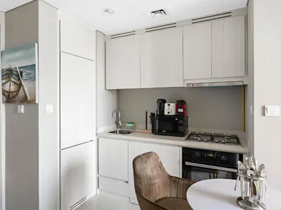 a kitchen with white cabinets and a table with chairs at Premium 1 BDR in Zada Tower-Business Bay in Dubai