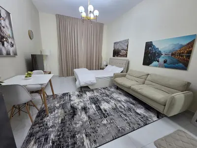 a living room with a couch and a table at Wavez 06 Well Furnished Studio in Liwan in Dubai