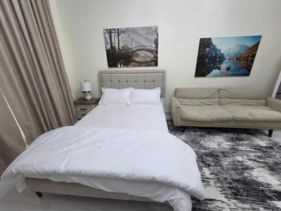 a bedroom with a white bed and a couch at Wavez 06 Well Furnished Studio in Liwan in Dubai