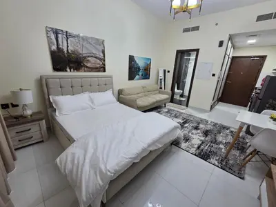 a bedroom with a large bed and a couch at Wavez 06 Well Furnished Studio in Liwan in Dubai