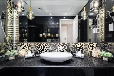 a bathroom with a white sink and black tiles at Ultra-Luxe Breathtaking Canal Views l Business Bay in Dubai
