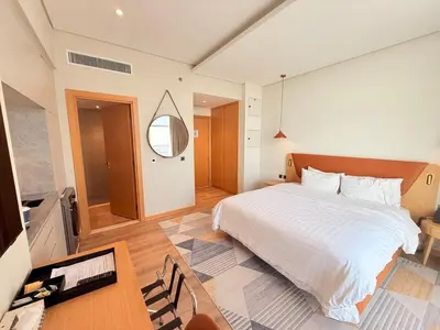 a bedroom with a bed and a table and a mirror at Novotel JVT Studio 5 Star Amenities Access in Dubai