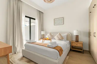 a white bedroom with a bed and a table at VayK - Modern 4 BD Townhouse with Private Garden in Damac Lagoons in Dubai
