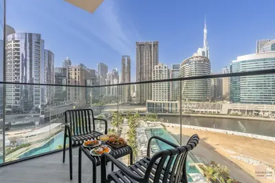 a balcony with two chairs and a table with food on it at Réveille Face au Burj Khalifa Vu Canal & Piscine in Dubai
