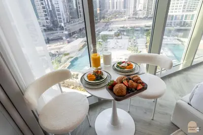 a table with a plate of food in a room with a window at Réveille Face au Burj Khalifa Vu Canal & Piscine in Dubai