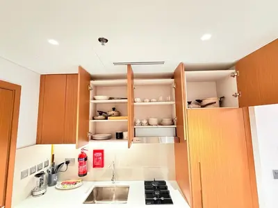 a small kitchen with wooden cabinets and a sink at City Glow Comfort Studio - Oasis Pool in Dubai