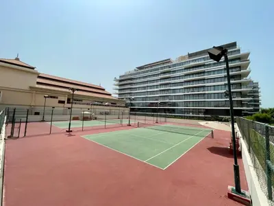 a tennis court in front of a large building at Palm Horizon | Luxury Anantara Studio in Dubai