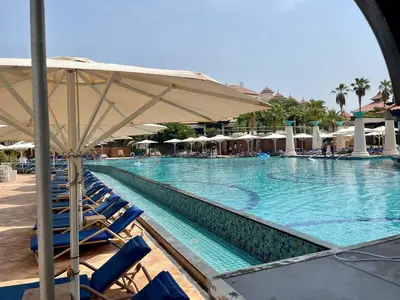 a large swimming pool with blue chairs and umbrellas at Palm Horizon | Luxury Anantara Studio in Dubai