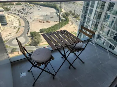a bench and chairs on a balcony with a view of a city at Brand new Studio in Skyz by Danube Arjan in Dubai