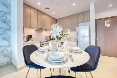 a dining room with a white table and blue chairs at Luxury Sea View 1BR in JBR with easy Bluewaters Access in Dubai