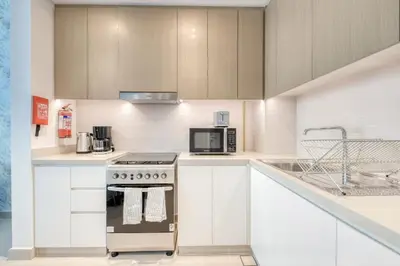 a kitchen with white cabinets and a stove top oven at Luxury Sea View 1BR in JBR with easy Bluewaters Access in Dubai