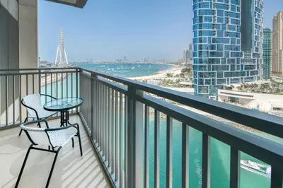 a balcony with two chairs and a table and the ocean at Luxury Sea View 1BR in JBR with easy Bluewaters Access in Dubai