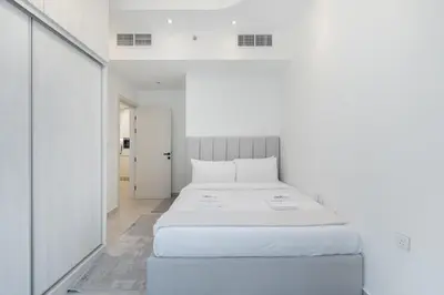 a bedroom with a white bed in a white room at Luxury 1BR Apartment in Binghatti Mirage JVC Dubai in Dubai