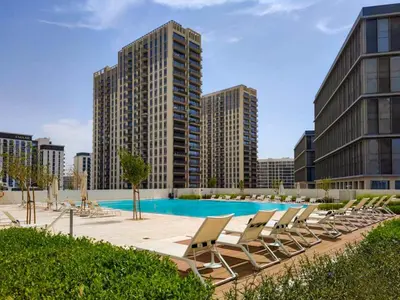 a pool with lounge chairs and tall buildings at Stunning 1 B R in Dubai Hills in Dubai