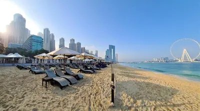 a beach with chairs and umbrellas and the ocean at Jumeirah Beach Luxury Collective in Dubai