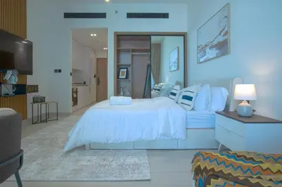 a bedroom with a white bed and a television at Amazing Amenities Studio JVC Gym Near Mall in Dubai