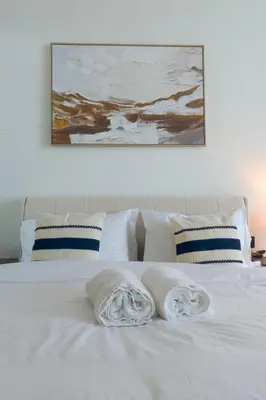 a white bed with two towels on top of it at Amazing Amenities Studio JVC Gym Near Mall in Dubai