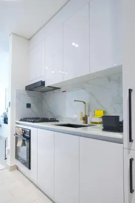 a white kitchen with white cabinets and a sink at Amazing Amenities Studio JVC Gym Near Mall in Dubai