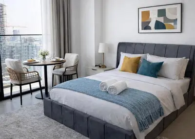 a bedroom with a large bed with towels on it at Studio in JVC I Pool View I Near Mall & Dining in Dubai
