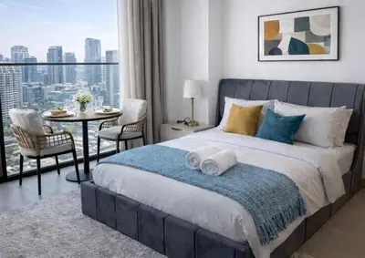 a bedroom with a large bed and a table with chairs at Studio in JVC I Pool View I Near Mall & Dining in Dubai