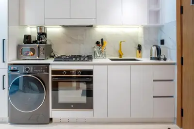 a kitchen with a washing machine and a stove at Studio in JVC I Pool View I Near Mall & Dining in Dubai
