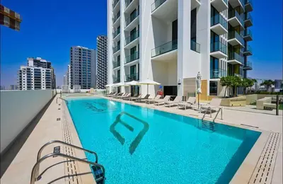 a swimming pool with chairs and a building at Elegant JVC Studio I Gym Access I Prime Location in Dubai