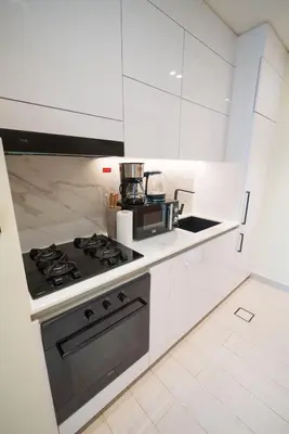 a kitchen with white cabinets and a stove top oven at Elegant JVC Studio I Gym Access I Prime Location in Dubai