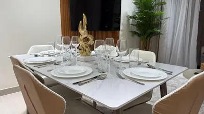a white table with white plates and wine glasses at Stylish 2Bedroom JVC I Comfort I Epic Pool in Dubai