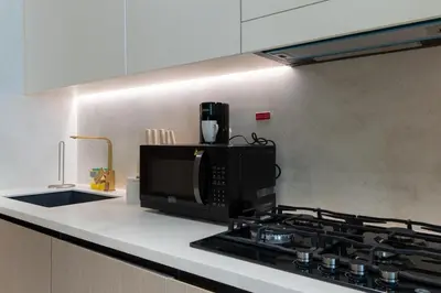a kitchen with a microwave oven and a stove at Cozy JVC Studio I Pool & Gym I Fully Furnished in Dubai