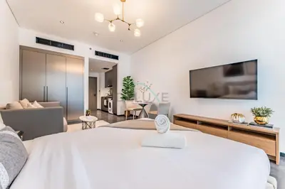 a bedroom with a large white bed and a living room at Tranquil Studio Just minutes Drive to Dubai Attraction, O10 Building Al Jaddaf by Deluxe Holiday Homes in Dubai