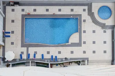 a large swimming pool in a building with blue chairs at Casa Aruri,1B Marina Escape Near Metro and Marina Mall in Dubai