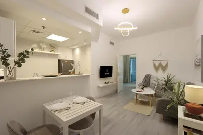 a white living room with a table and chairs at Casa Aruri,1B Marina Escape Near Metro and Marina Mall in Dubai