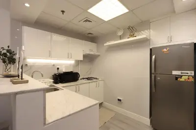 a kitchen with white cabinets and a stainless steel refrigerator at Casa Aruri,1B Marina Escape Near Metro and Marina Mall in Dubai