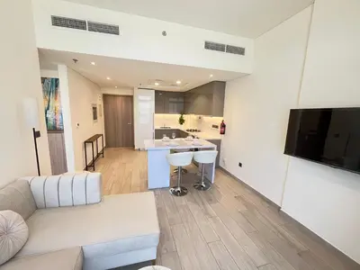 a living room with a white couch and a kitchen at Chic French-Riviera Vibe - Burj View 1BR in Dubai
