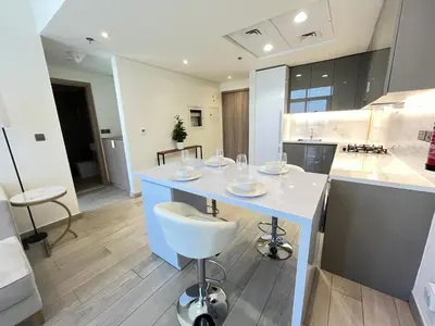 a kitchen with a white island with a white chair at Chic French-Riviera Vibe - Burj View 1BR in Dubai