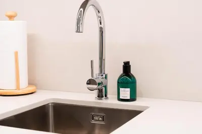 a kitchen sink with a bottle of wine next to it at 1BR Burj View Apartment In Dubai Creek Harbour in Dubai