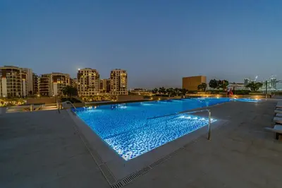 a large swimming pool in a city at night at 1BR Burj View Apartment In Dubai Creek Harbour in Dubai